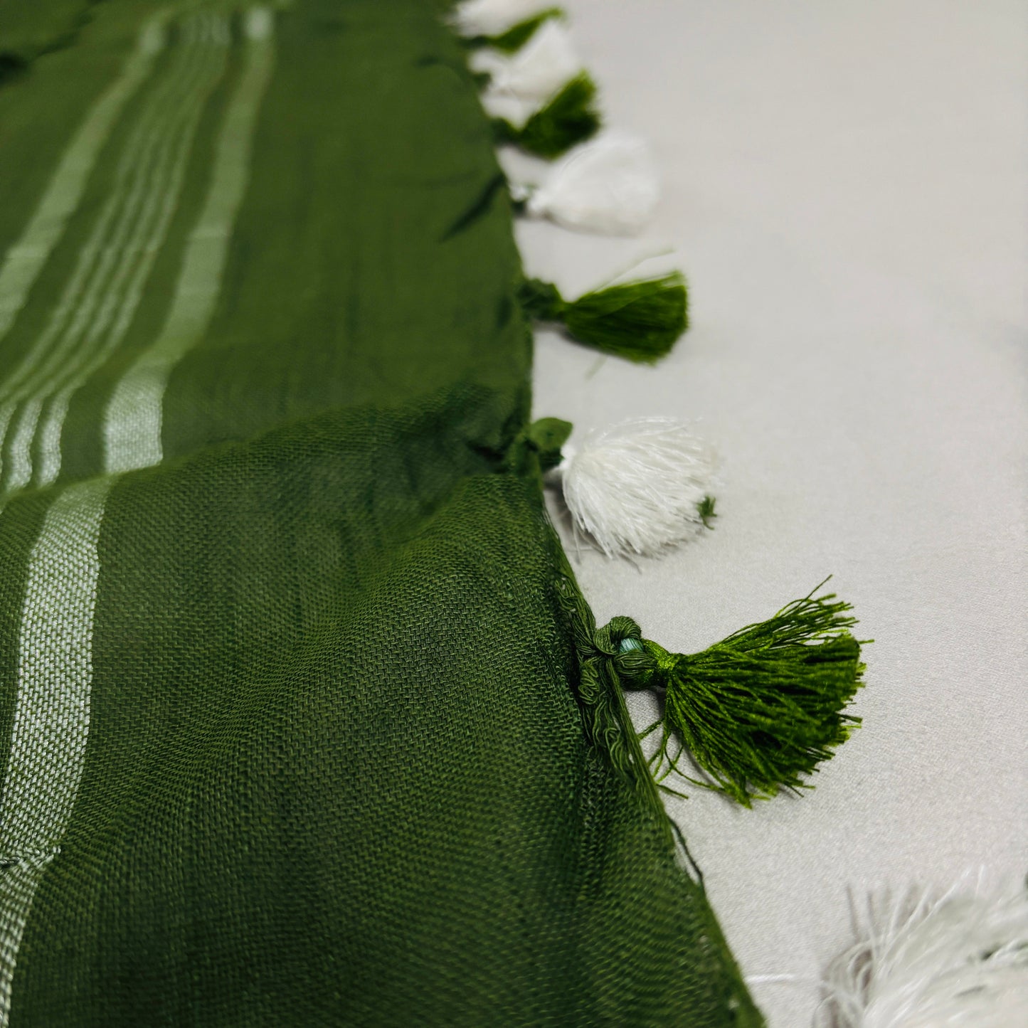 Green linen Shuchi Label saree with silver border on a white background