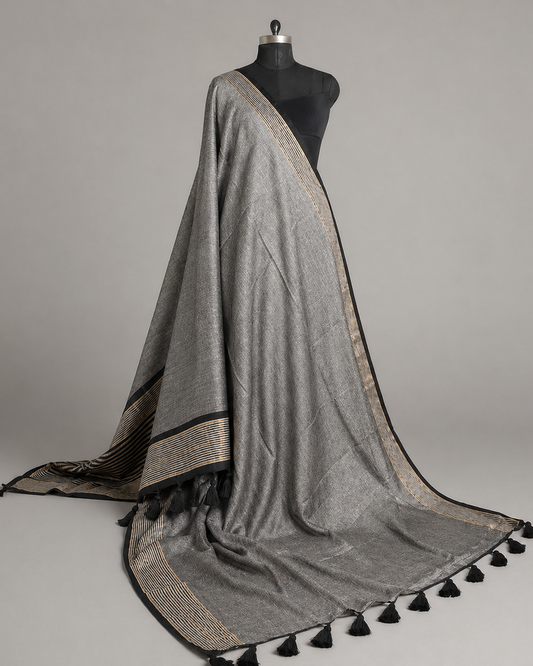 Gray saree with black and gold striped pallu draped over a mannequin against a gray background