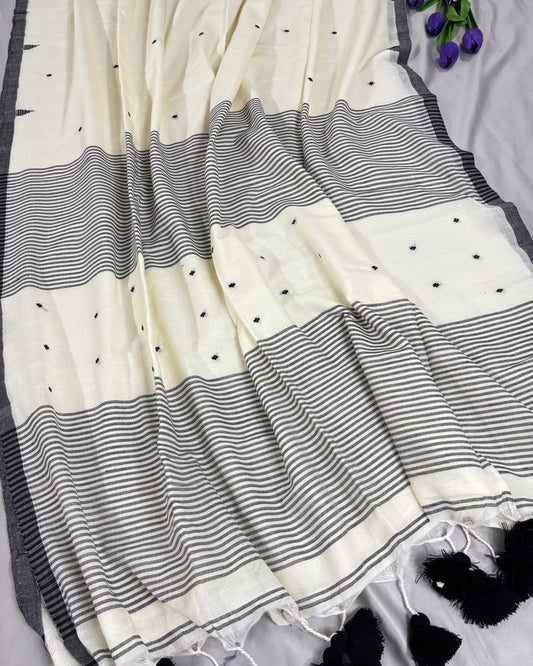 White saree with black temple border and tassel pallu on a gray surface