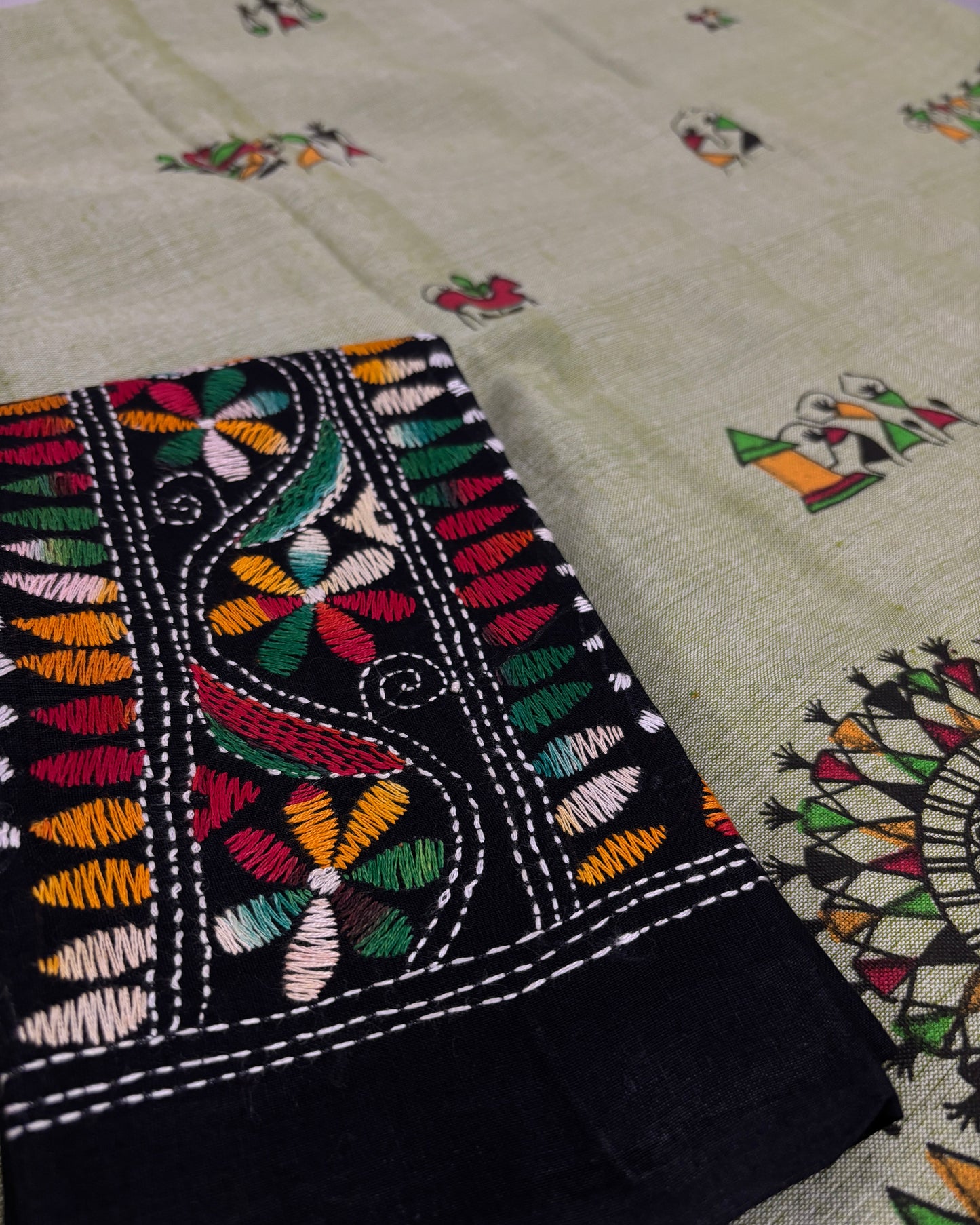 Close-up of embroidered fabric with colorful patterns on a light green saree