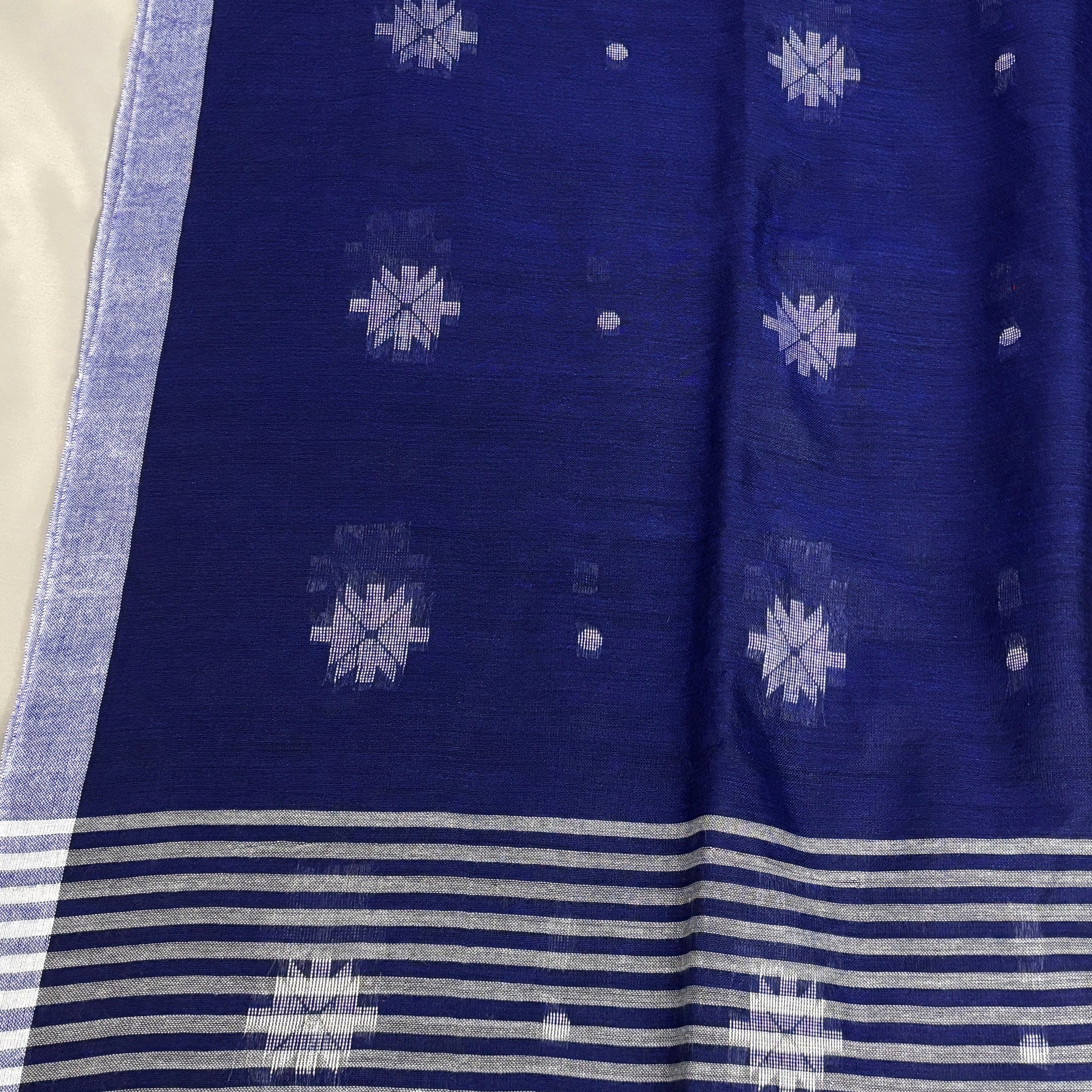 Blue cotton saree with white patterns and stripes on a light gray background