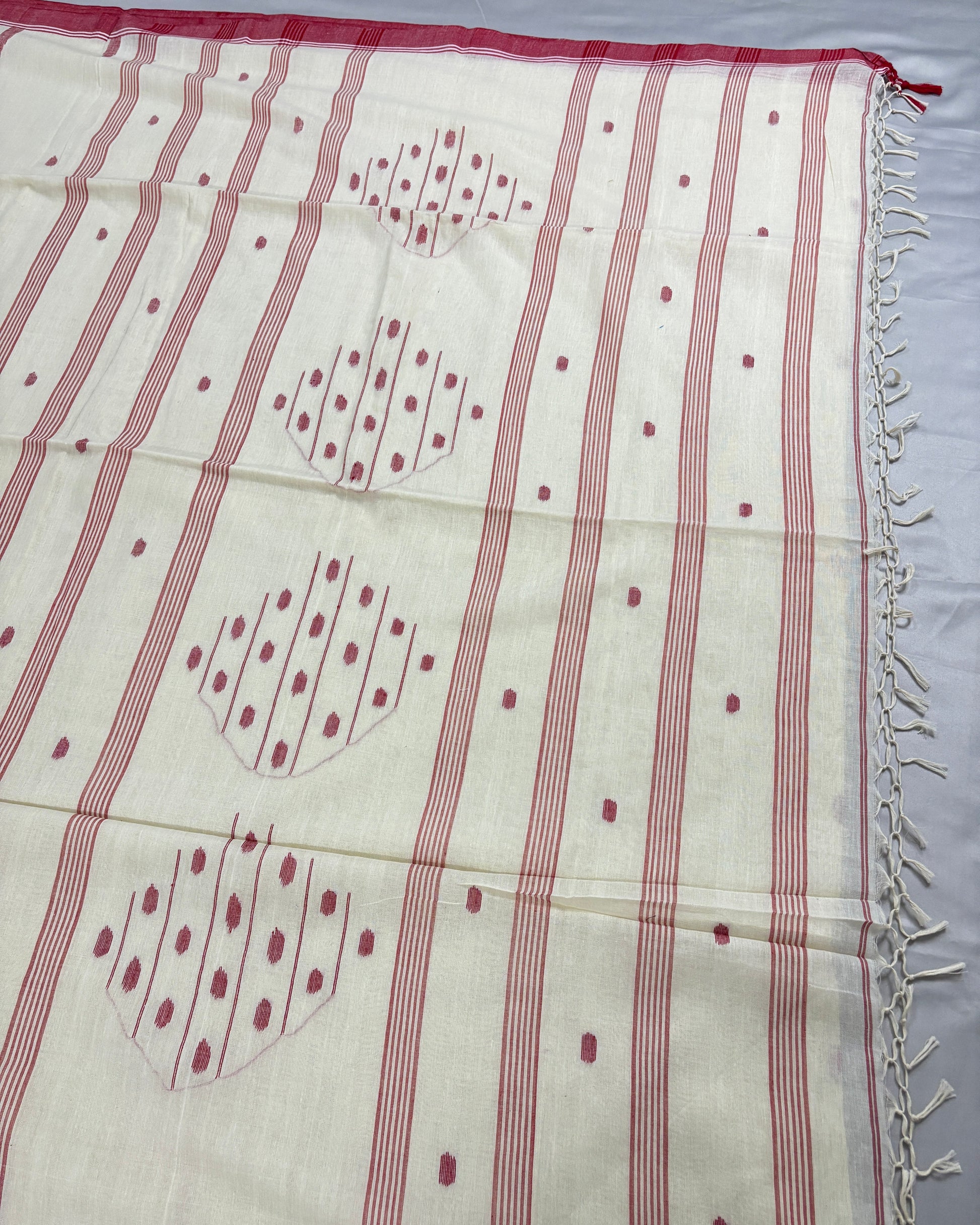 White cotton saree with red temple border on a light gray background