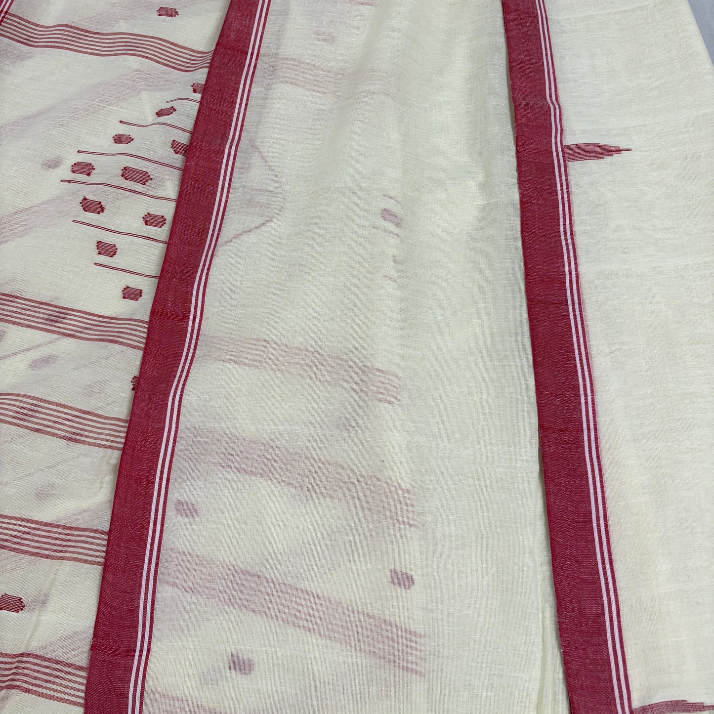 White saree with red border on a plain background