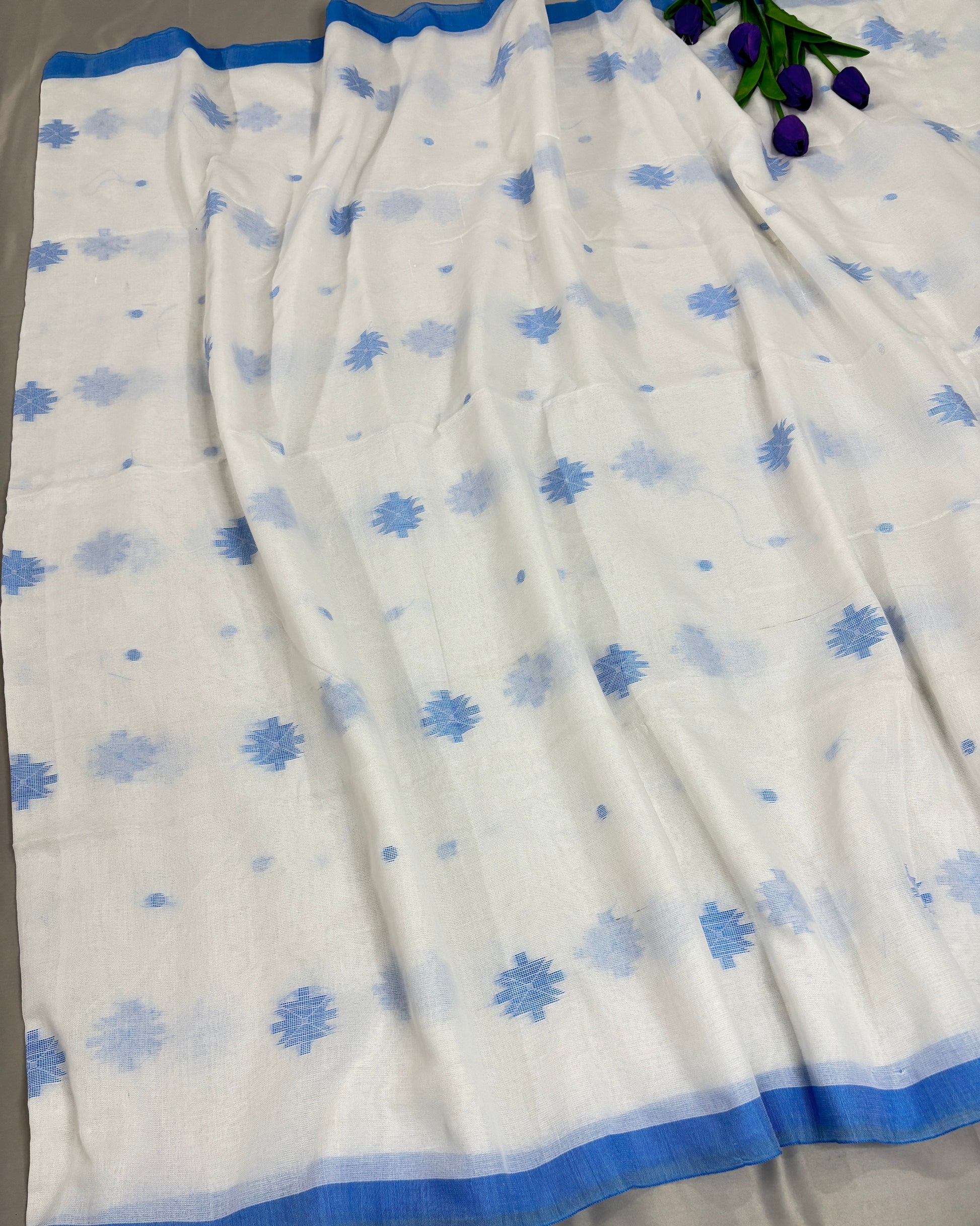 White saree with blue floral patterns on a gray background