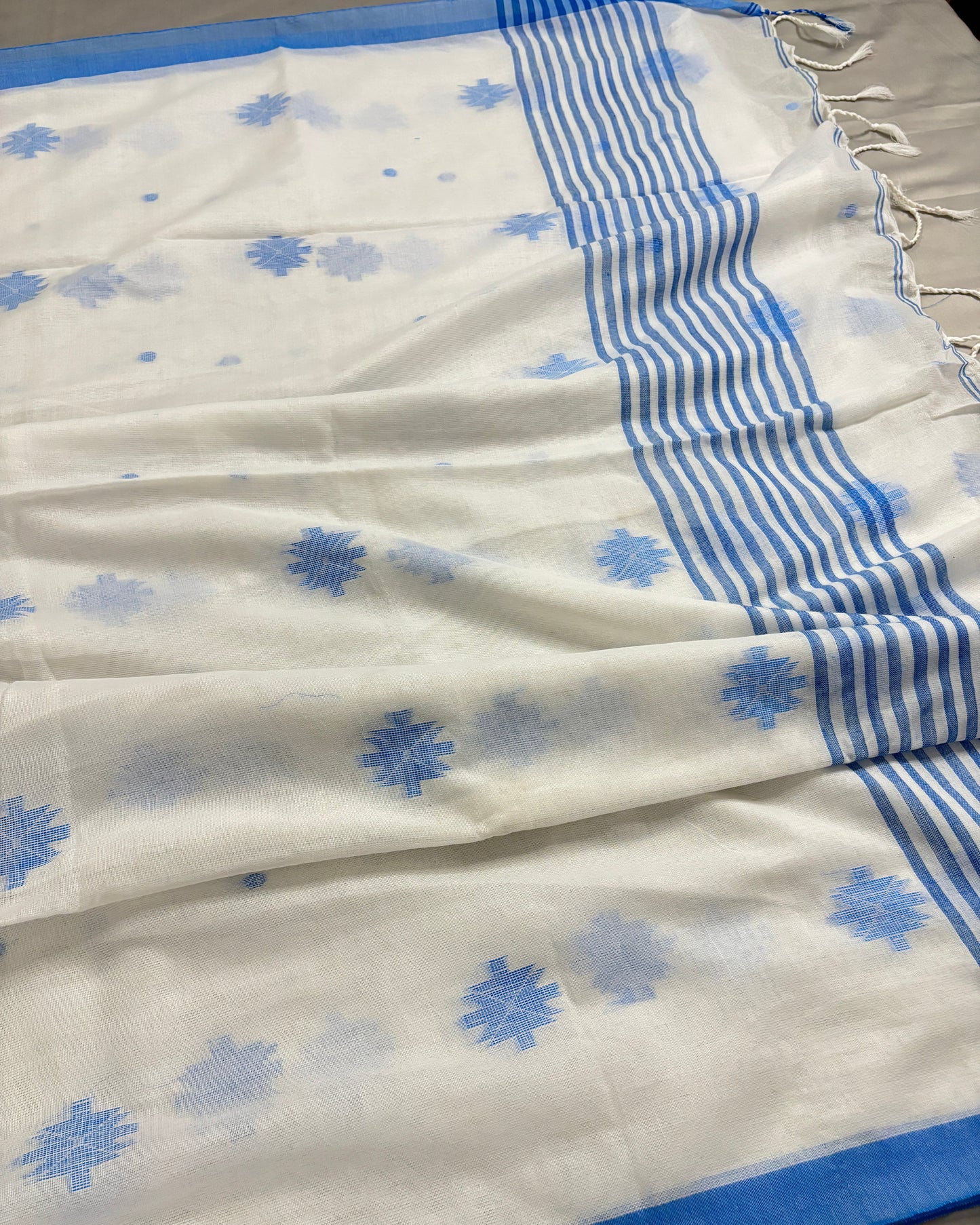 White Shuchi Label saree with blue floral patterns and blue border