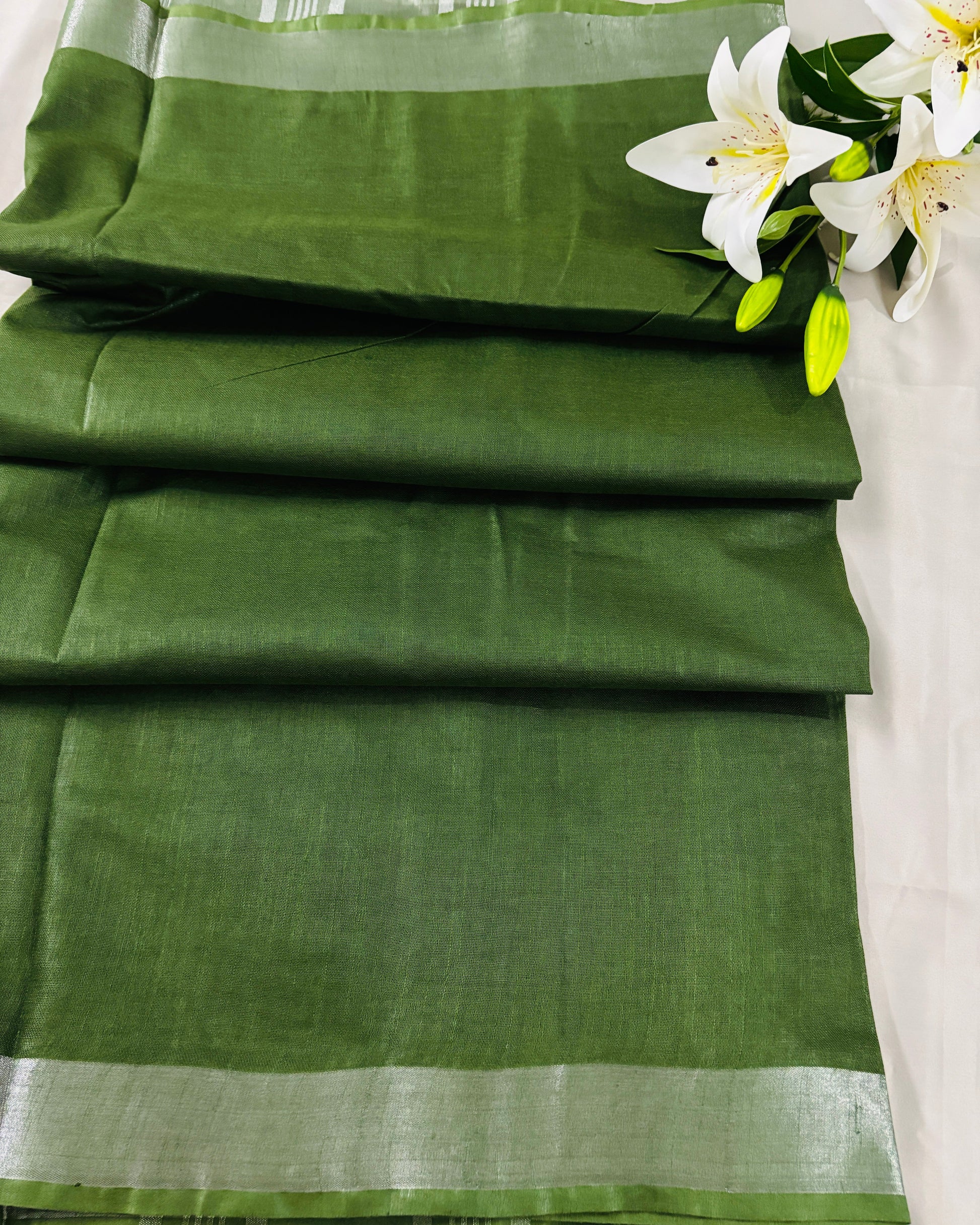 Green linen Shuchi Label saree with silver border on a white background