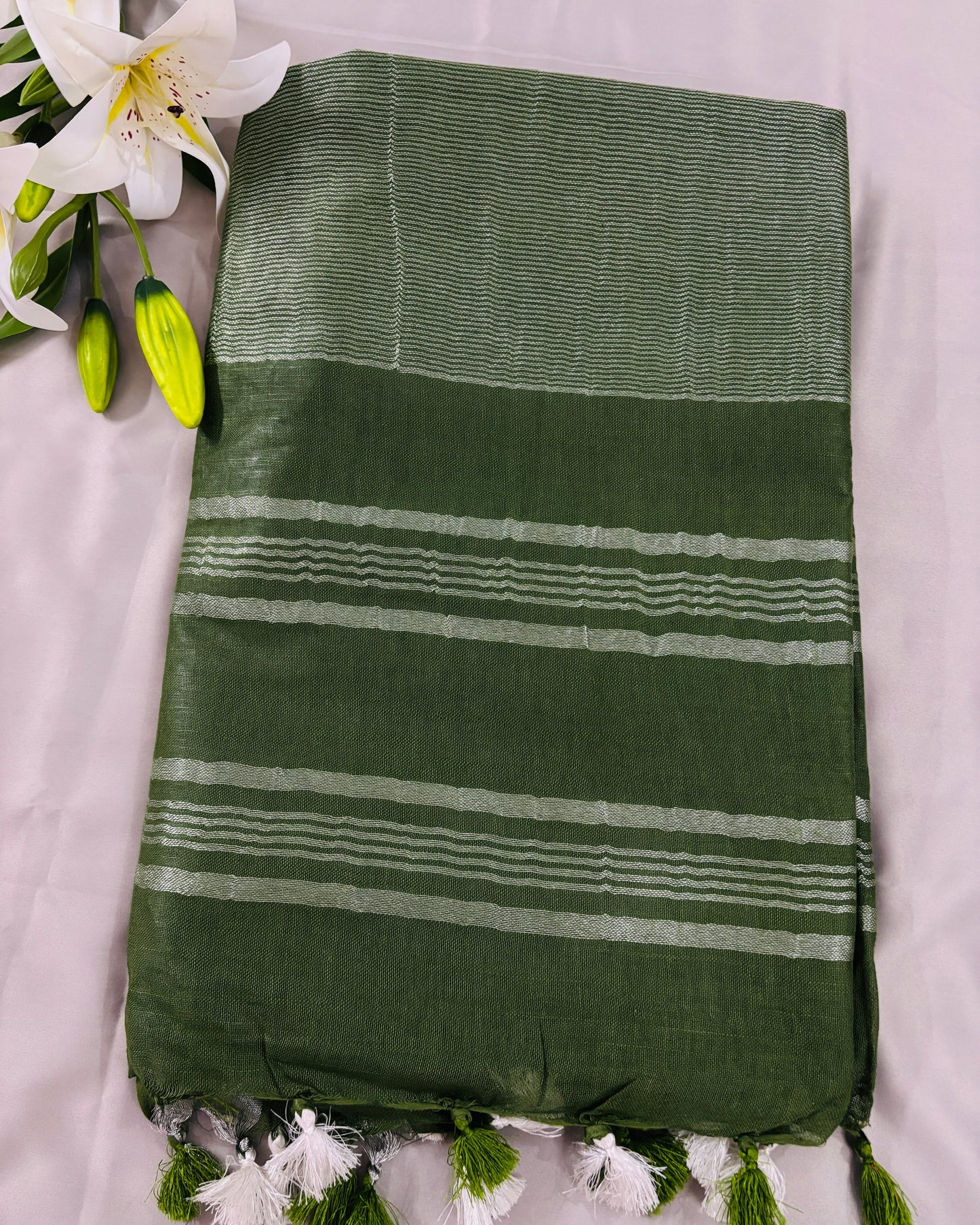 Green linen Shuchi Label saree with silver border on a grey background