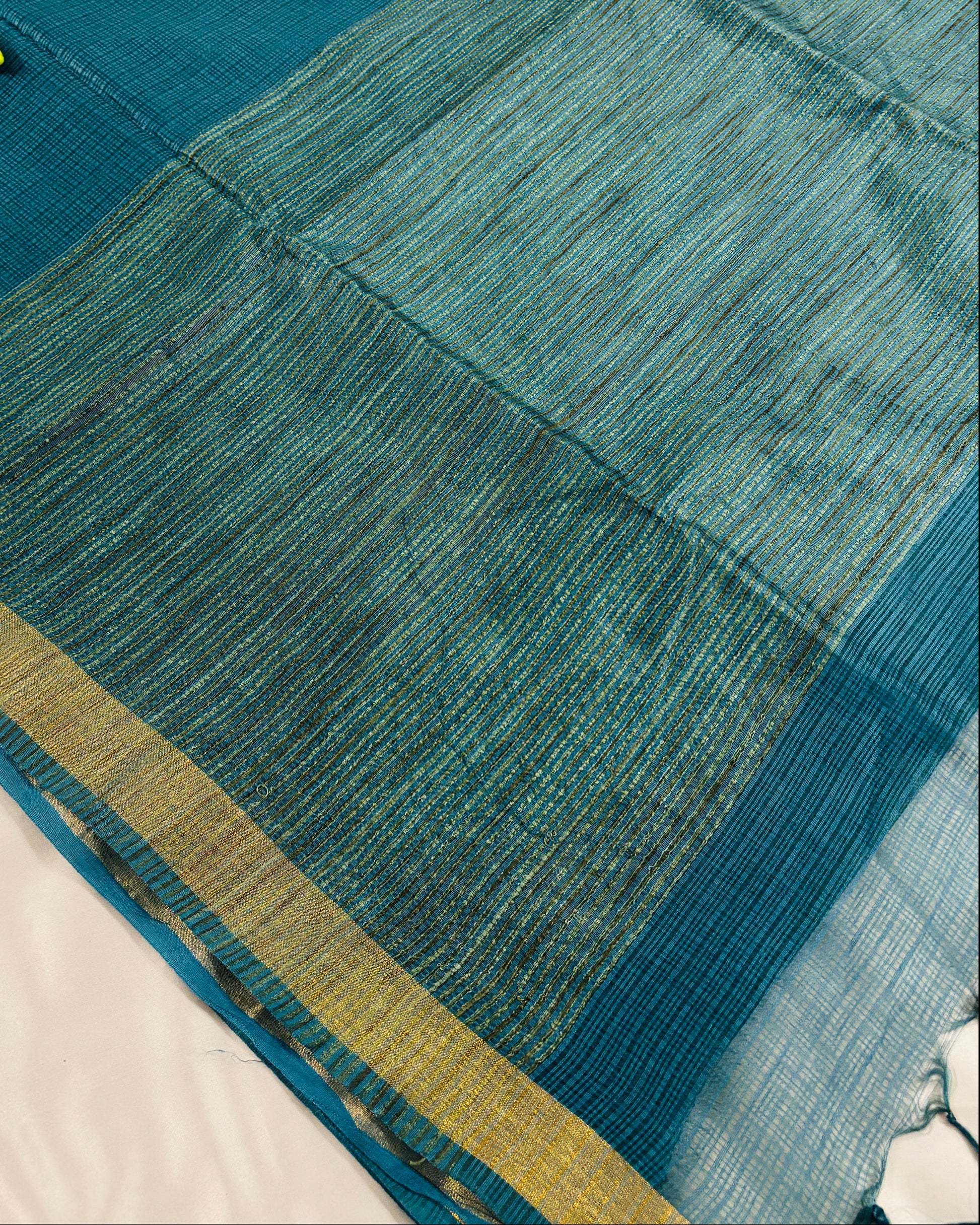 Green kota doria silk saree with gold border on a grey background