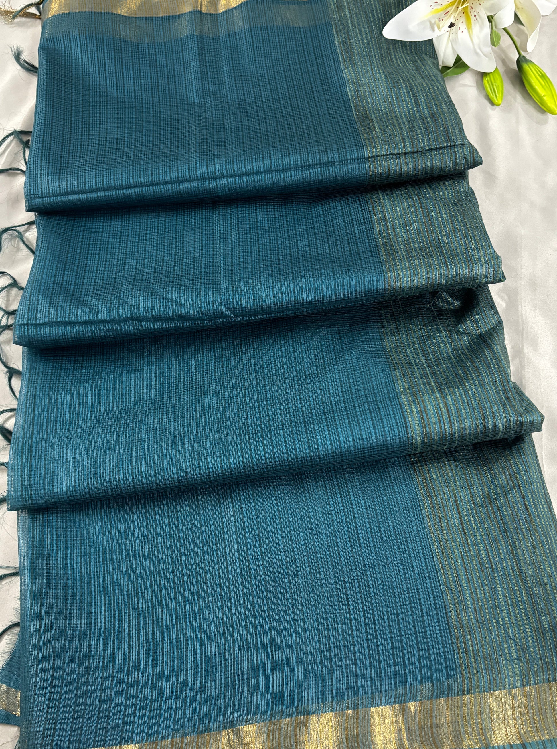 Green kota doria silk saree with gold border on a grey background