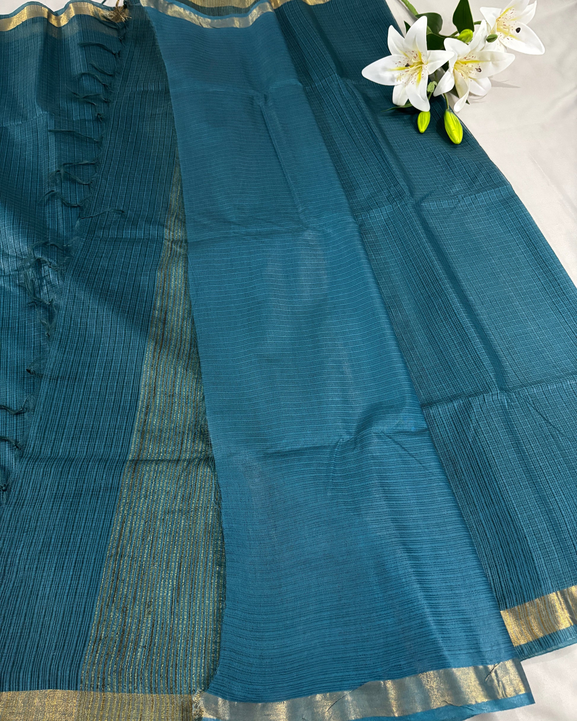 Green kota doria silk saree with gold border on a grey background